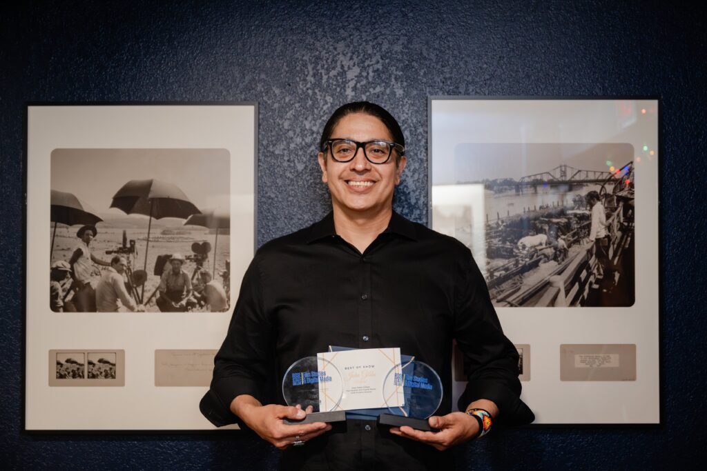 Smiling man holding two Rose State College Film Studies and Digital Media awards and a Best of Show certificate.