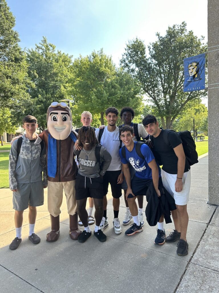 A group of male students pose with Rowdy the Raider outside in the mall on campus. 