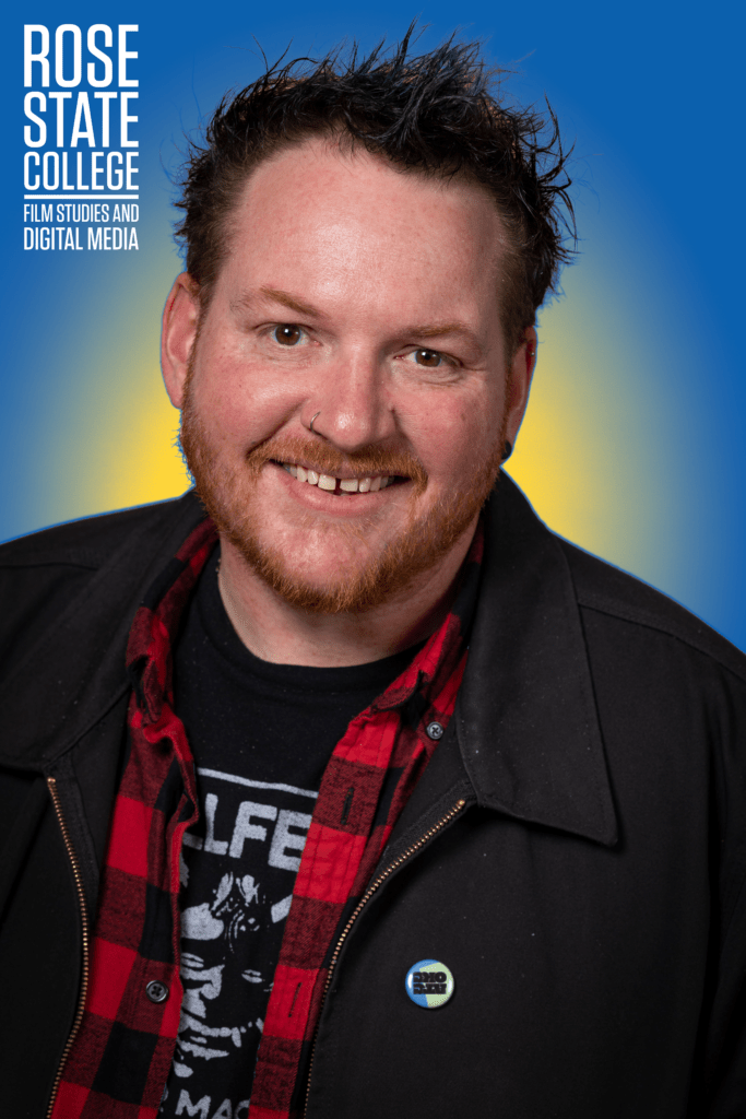 Headshot of a Rose State College Film Studies and Digital Media instructor smiling against a blue background.