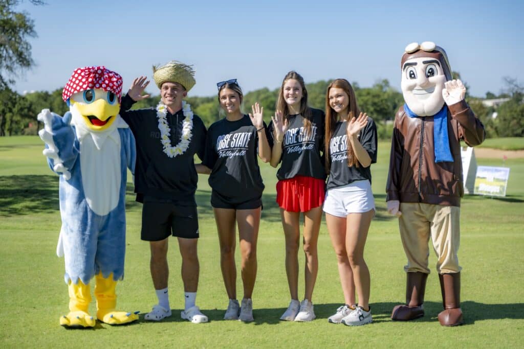 Rosie the Eagle and Rowdy the Raider pose with one RSC male student and three RSC female students one the golf course