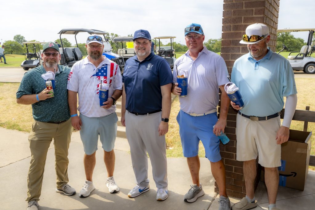 Five men in golf attire pose together at the Rose State College Foundation Golf Tournament, with golf carts and the course visible in the background.